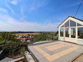 An outdoor area with a glass railing overlooking a landscape at Ael Y Bryn Dyserth