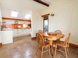 A dining room with a round table and chairs at Ael Y Bryn in Dyserth