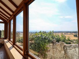 A conservatory with large windows overlooking a landscape at Ael Y Bryn in Dyserth