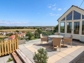 An outdoor patio with a round table and chairs at Ael Y Bryn Dyserth