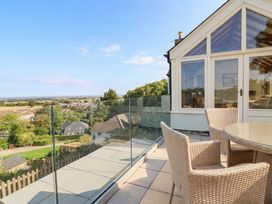 An outdoor terrace with a glass railing and seating at Ael Y Bryn Dyserth