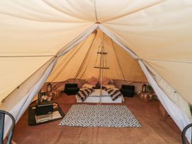 Interior of a bell tent with a bed pillows blankets wood stove and lanterns at Bell tent 1 in Camerton near Timsbury