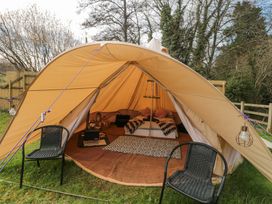 A bell tent with a bed pillows rugs chairs and a lantern at Bell tent 1 in Camerton near Timsbury