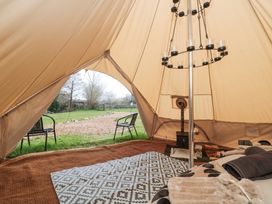Inside view of a bell tent with a patterned rug blankets a wood stove and two chairs outside in a grassy area at Bell tent 1 in Camerton near Timsbury