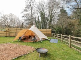 A bell tent with chairs and rugs outside in a fenced grassy area at Bell tent 1 Camerton near Timsbury