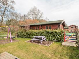 A garden with a purple picnic table and swingset next to a wooden cabin at Bell tent 1 in Camerton near Timsbury