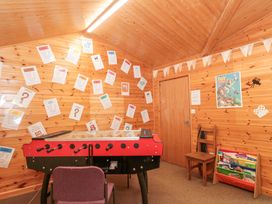 A game room with a foosball table chair and wooden shelves with books at Bell tent 1 in Camerton near Timsbury