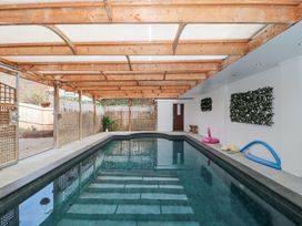 An indoor swimming pool with wooden beams and lattice fencing at Bell tent 1 in Camerton near Timsbury