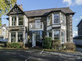 A stone building with large bay windows and a small balcony at Fir Trees in Windermere