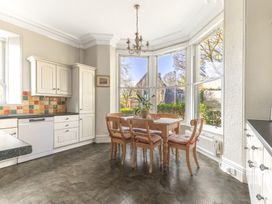A kitchen with a wooden dining table and chairs near large windows at Fir Trees in Windermere