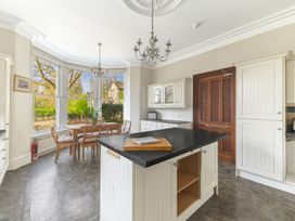 A kitchen with a central island and dining table by large windows at Fir Trees in Windermere