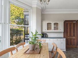 A dining area with a wooden table and chairs a plant on the table white cabinets and a wooden door at Fir Trees in Windermere