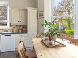 A kitchen with cream cabinets a wood table and chairs with a potted plant on the table at Fir Trees in Windermere