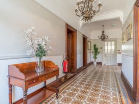A hallway with a wooden table holding a vase of white flowers chandeliers and a patterned tiled floor at Fir Trees in Windermere