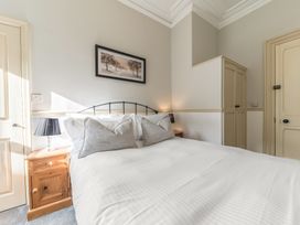 A bedroom with a double bed two bedside tables with lamps a framed picture and a built in wardrobe at Fir Trees in Windermere