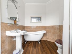 A bathroom with a pedestal sink a clawfoot bathtub a toilet and a framed picture on the wall at Fir Trees in Windermere