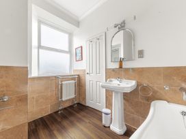 A bathroom with a pedestal sink mirror bathtub window and a radiator at Fir Trees in Windermere