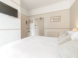 A bedroom with a bed pillows a wall-mounted television and framed pictures at Fir Trees in Windermere