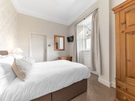 A bedroom with a bed pillows curtains wardrobe and a wall-mounted television at Fir Trees in Windermere