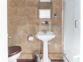 A bathroom with a pedestal sink a mirror and a shower enclosure at Fir Trees in Windermere