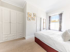 A bedroom with a large bed white wardrobe and window with curtains at Fir Trees in Windermere
