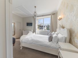 A bedroom with a white bed and bedside tables a window with curtains and a wall-mounted television at Fir Trees in Windermere
