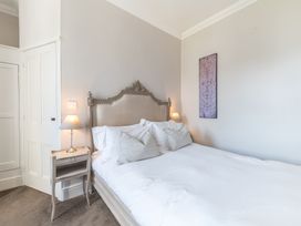 A bedroom with a double bed two bedside tables with lamps and a decorative panel on the wall at Fir Trees in Windermere