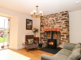 A living room with a fireplace and a chair at Higher Weekaborough Farm in Coombe Fishacre near Ipplepen