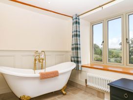 A bathroom with a bathtub and window at Higher Weekaborough Farm near Ipplepen