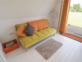 A snug with a green sofa and pillows at A-frame in Monewden near Otley, Suffolk