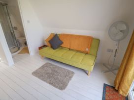 A room with a couch and fan near a bathroom at A-frame in Monewden near Otley, Suffolk