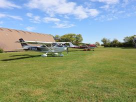 Two airplanes parked on grass near a hangar at A-frame in Monewden near Otley, Suffolk