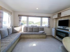 A living room with a corner sofa a television and a fireplace at 31A Foxburrow Hang Fritton near Belton Norfolk