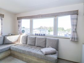 A corner sofa with cushions under windows with curtains and letters spelling dream at 31A Foxburrow Hang in Fritton near Belton Norfolk