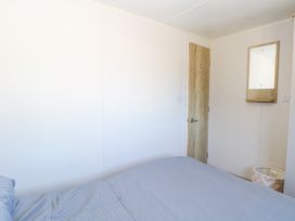 A bedroom with a bed covered in blue bedding a wooden door a mirror on the wall and a basket at 31A Foxburrow Hang in Fritton near Belton Norfolk