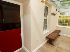 A hallway with a wooden bench a window and a red door at Kirkland Howe Cottage in Arlecdon