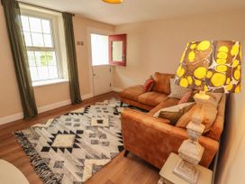 A sitting room with a brown sectional sofa patterned rug and patterned lampshade at Kirkland Howe Cottage in Arlecdon
