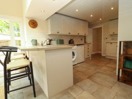 A kitchen with bar stools a washing machine and cabinets at Kirkland Howe Cottage in Arlecdon