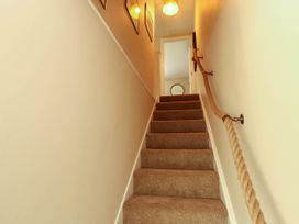 A carpeted staircase with rope handrail and framed pictures on the wall at Kirkland Howe Cottage in Arlecdon