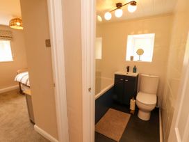 A bathroom with a toilet sink cabinet bathtub and a small window next to a bedroom with a bed and window at Kirkland Howe Cottage in Arlecdon