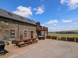 An outdoor area with a stone building and wooden deck at Llwyngwinau Isaf Barn Tynreithyn near Tregaron