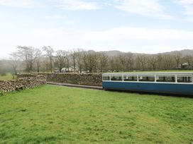 A train on railway tracks with trees and stone wall at Dakota in Boot