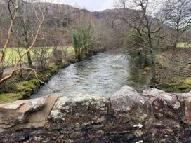 A river flowing alongside a stone wall with trees and grass near Dakota near Boot