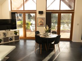 A dining area with a round table and four chairs near large wooden framed glass doors opening to an outdoor deck at The Green Monkey in North Hykeham