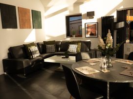 A living room with a black leather sectional sofa and a coffee table next to a dining table with placemats and flowers at The Green Monkey in North Hykeham