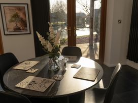 A dining table with placemats, coasters, a glass vase with flowers, and salt and pepper shakers by a glass door and a framed picture at The Green Monkey in North Hykeham