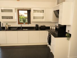 A kitchen with white cabinets black countertops a window with a plant and kitchen appliances at The Green Monkey in North Hykeham