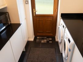 A laundry room with a washing machine, dryer, microwave, cabinets, and a wooden door at The Green Monkey in North Hykeham