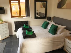 A bedroom with a bed with green pillows and folded towels a dresser a mirror and a window at The Green Monkey in North Hykeham