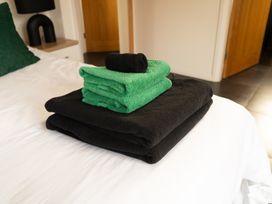 Folded black and green towels on a white bed in a bedroom at The Green Monkey in North Hykeham